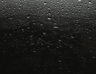 Rain drops on glass against black background