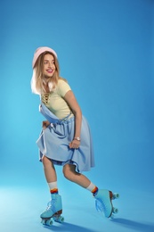 Young woman with retro roller skates on color background