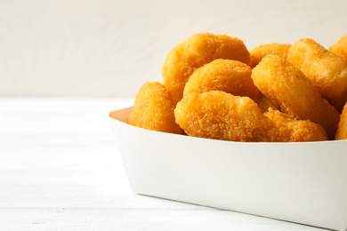 Tasty fried chicken nuggets on white wooden table, closeup