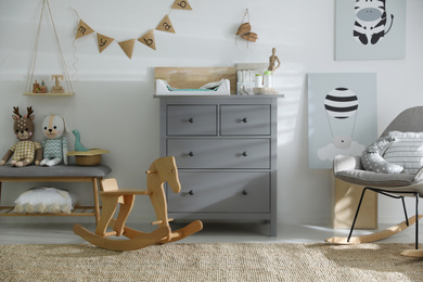 Photo of Beautiful baby room interior with toys, rocking chair and modern changing table