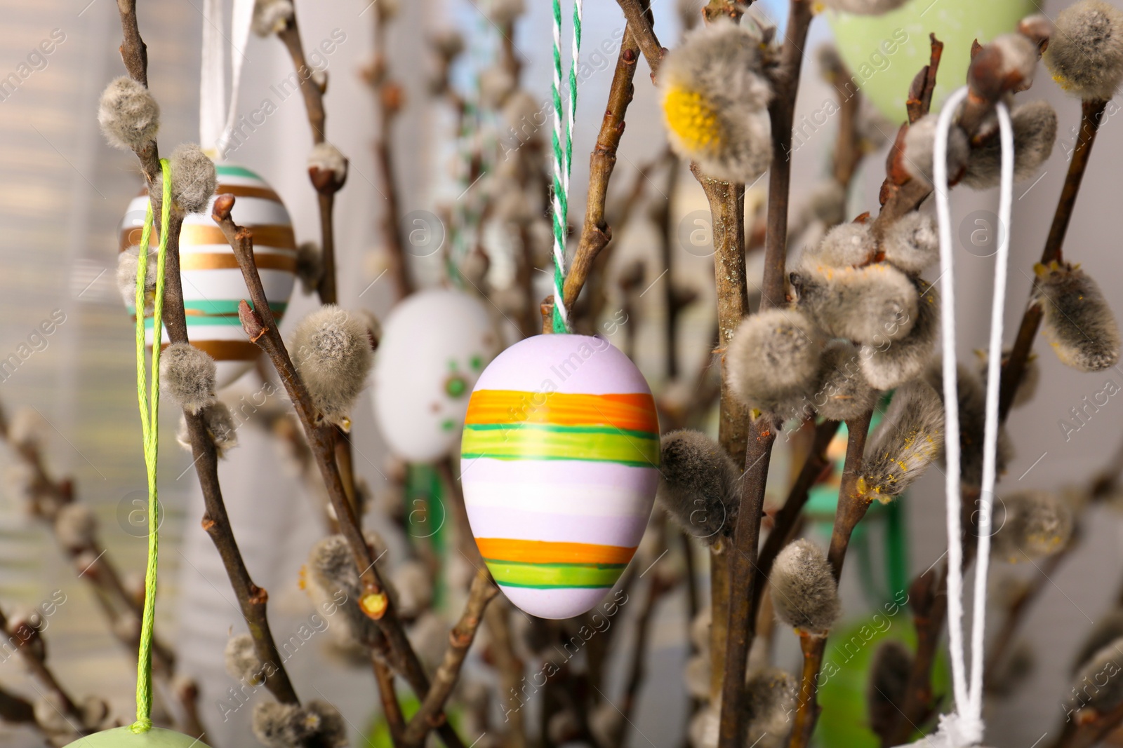 Photo of Beautiful willow branches with painted eggs indoors. Easter decor