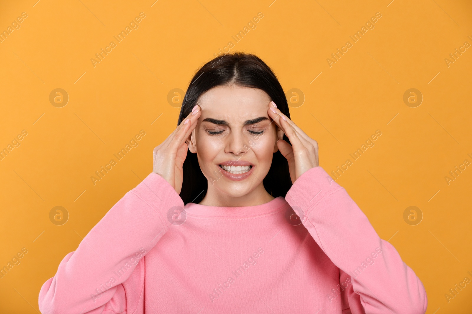 Photo of Woman suffering from migraine on yellow background