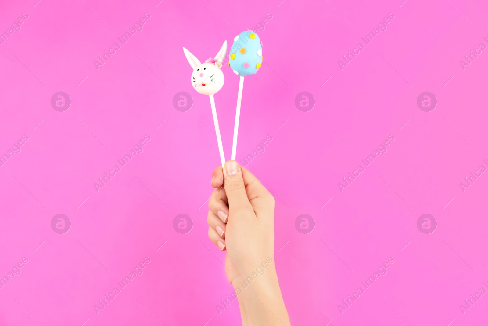 Photo of Woman with delicious cake pops on pink background, closeup. Easter holiday