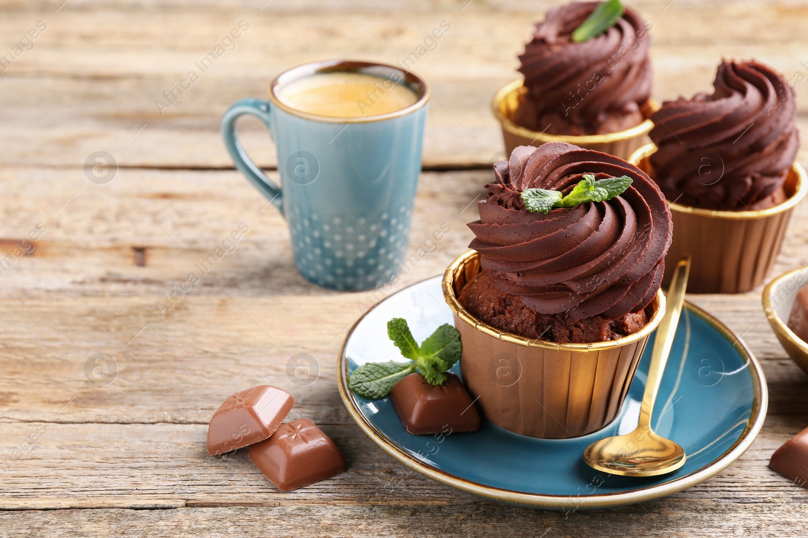 Photo of Delicious cupcakes with mint and chocolate pieces on wooden table. Space for text