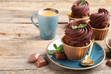 Photo of Delicious cupcakes with mint and chocolate pieces on wooden table. Space for text