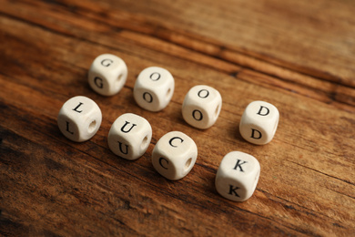 Photo of Cubes with phrase GOOD LUCK on wooden table, closeup