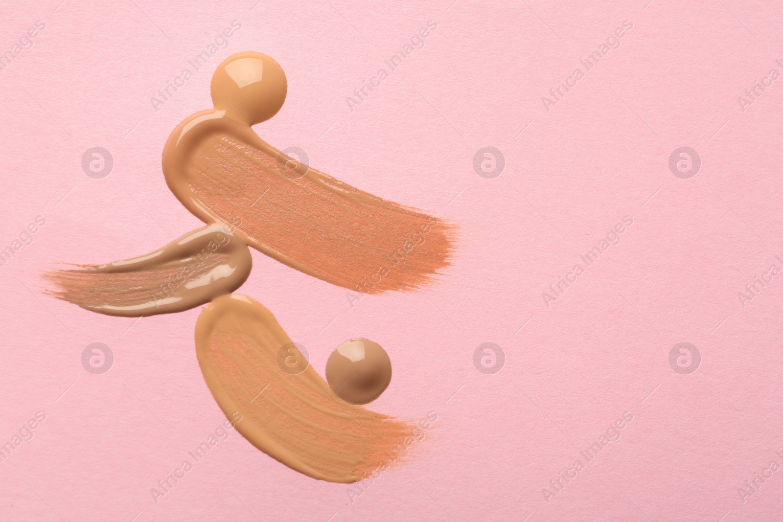 Photo of Samples of liquid skin foundation on pink background, top view. Space for text