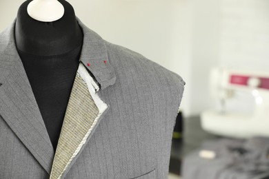 Photo of Mannequin with unfinished jacket in tailor shop, closeup. Space for text