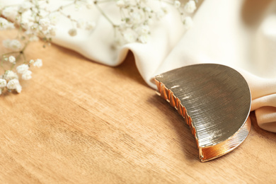 Photo of Stylish hair claw and flowers on wooden table, space for text