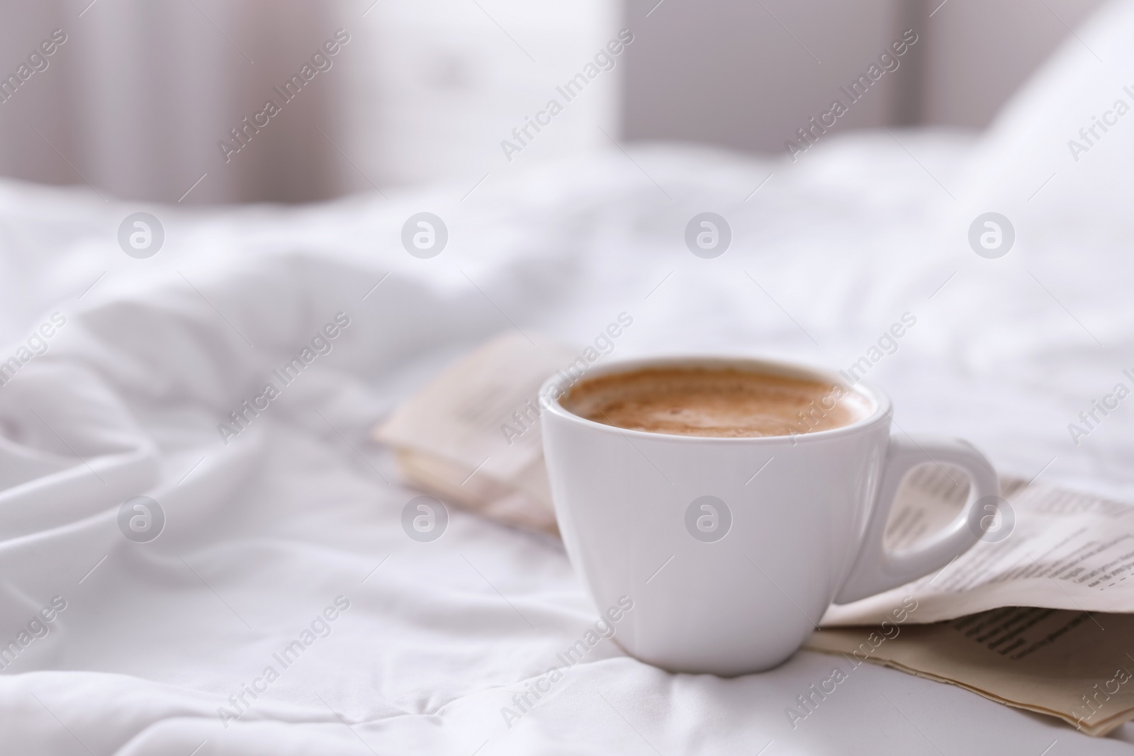 Photo of Morning coffee and newspaper on bed. Space for text