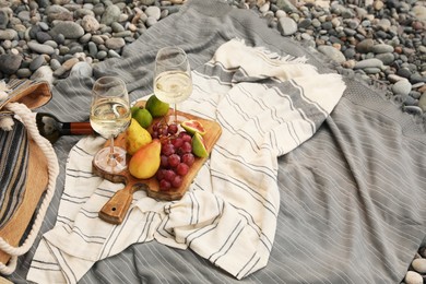 Photo of White wine and fresh fruits on picnic blanket outdoors