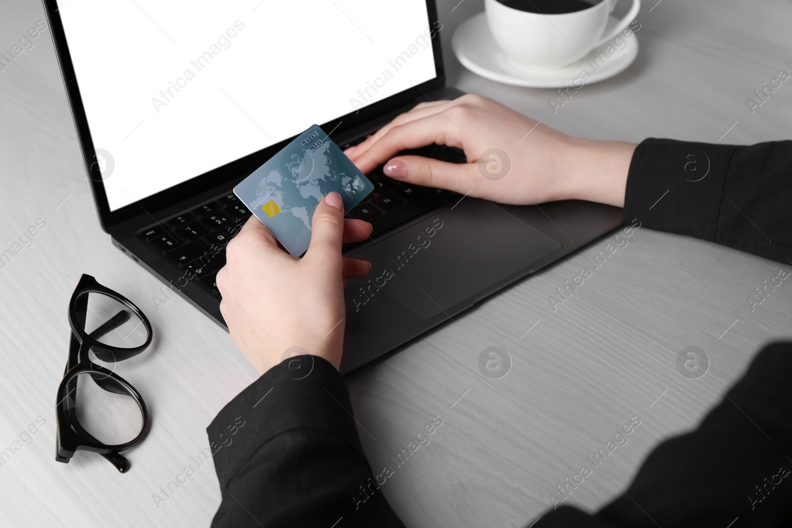 Photo of Online payment. Woman with laptop and credit card at white wooden table, closeup