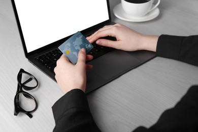 Photo of Online payment. Woman with laptop and credit card at white wooden table, closeup