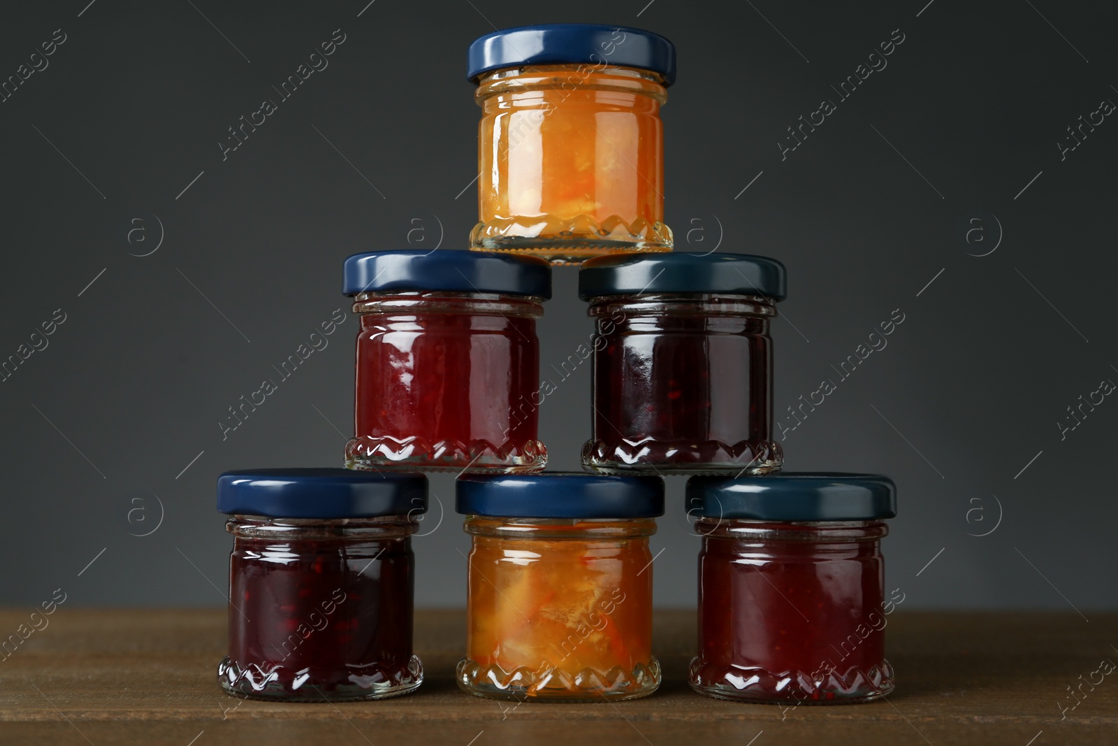 Photo of Jars of different jams on wooden table