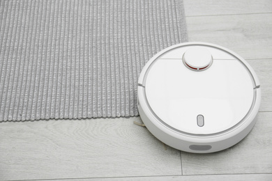 Photo of Hoovering floor with modern robotic vacuum cleaner indoors. Space for text