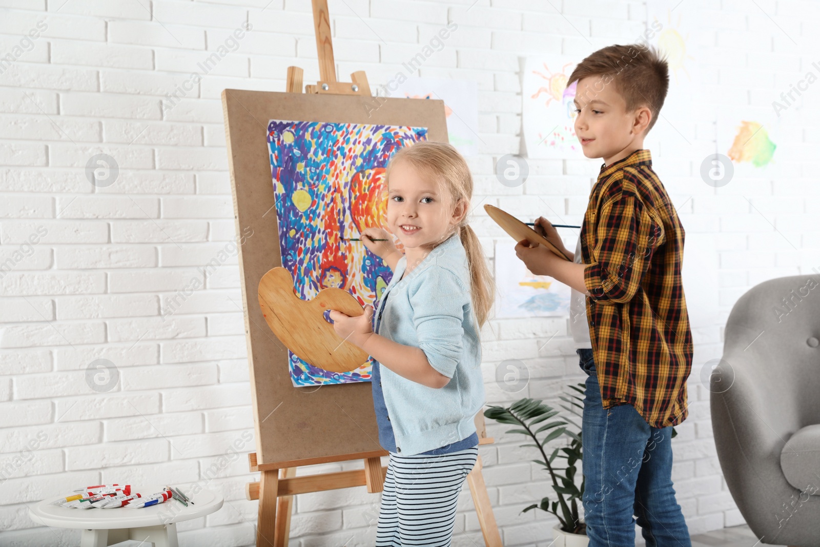 Photo of Cute little children painting on easel at home