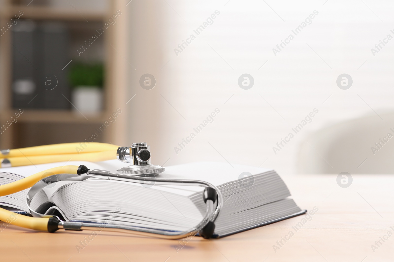 Photo of Book and stethoscope on wooden table indoors, space for text. Doctor education