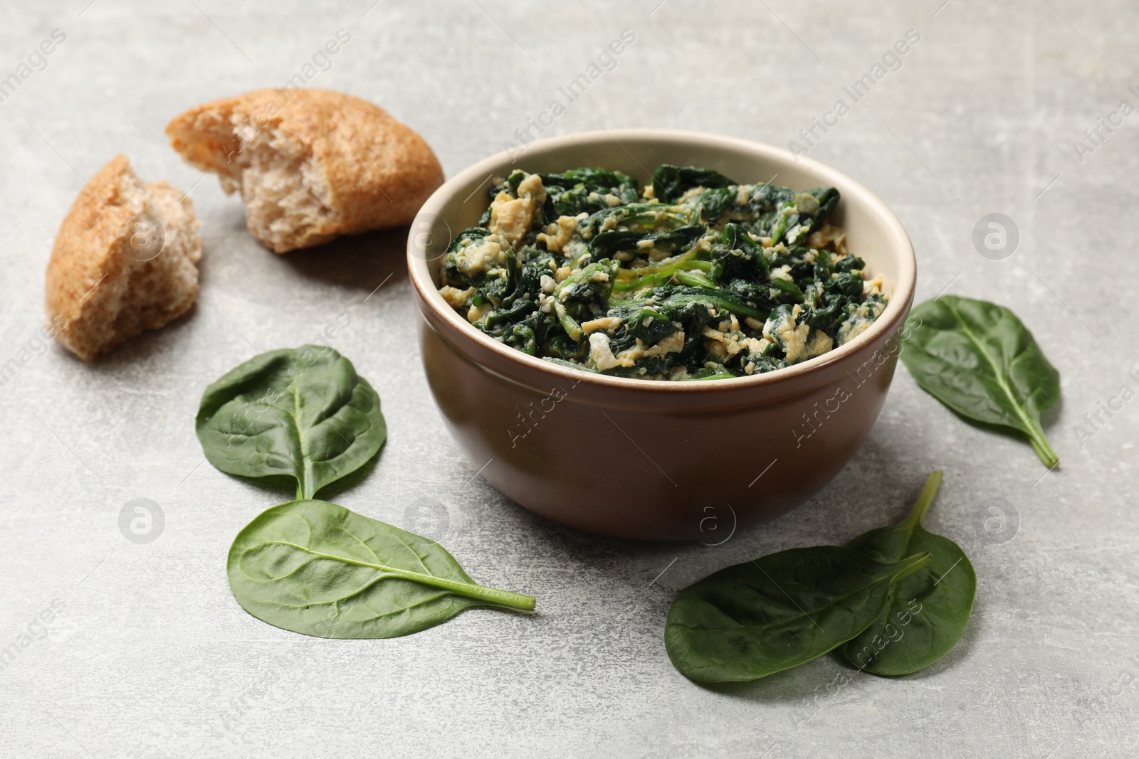 Photo of Tasty spinach dip with egg in bowl and bread on grey table