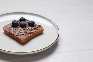 Photo of Toast with tasty nut butter, blueberries and nuts on white wooden table, closeup. Space for text