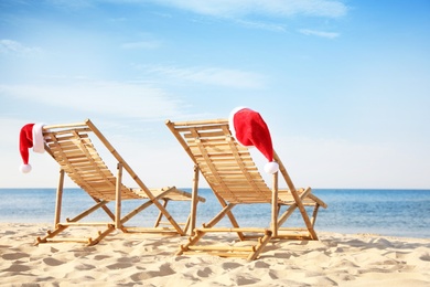 Photo of Sun loungers with Santa's hats on beach. Christmas vacation