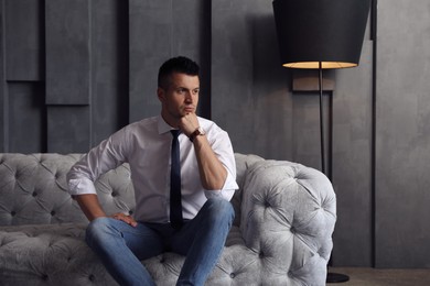 Photo of Handsome businessman on sofa indoors. Luxury lifestyle