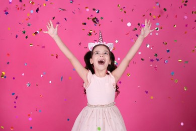 Photo of Adorable little girl and falling confetti on pink background