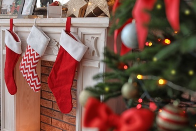 Photo of Decorative fireplace with red stockings near Christmas tree indoors