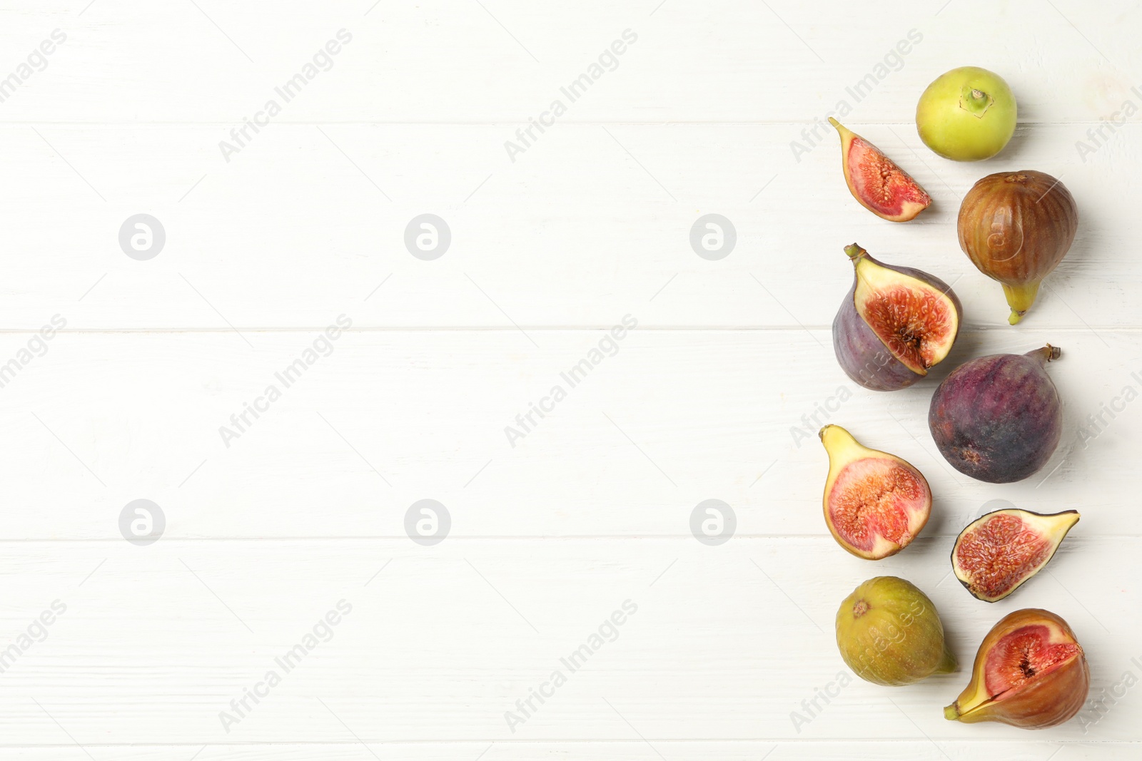 Photo of Tasty raw figs on white wooden table, flat lay. Space for text