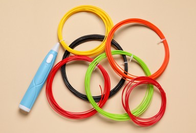 Photo of Stylish 3D pen and colorful plastic filaments on beige background, flat lay