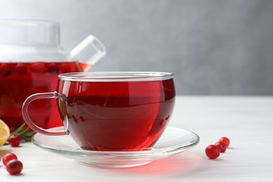 Tasty hot cranberry tea in glass cup and fresh berries on white wooden table