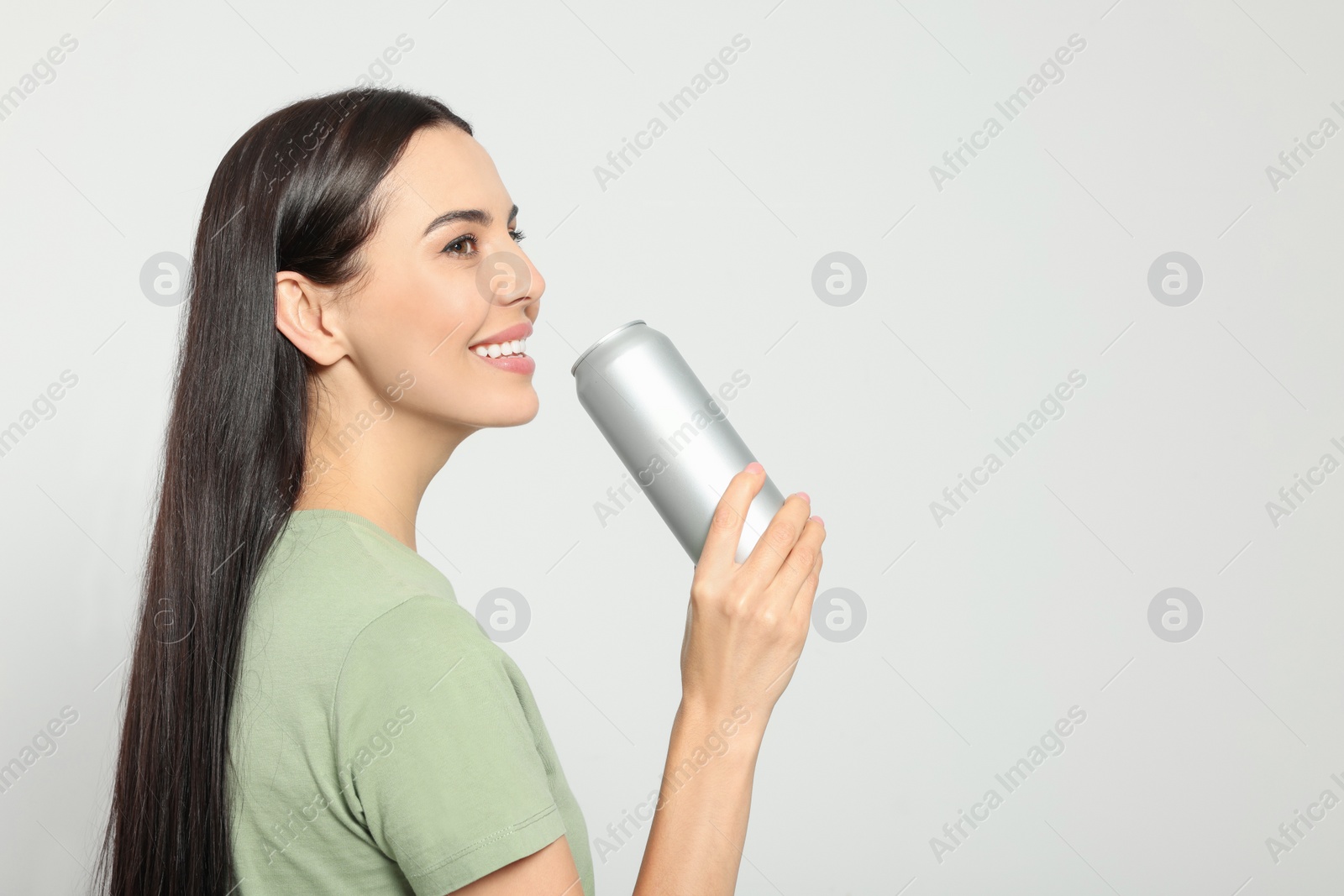 Photo of Beautiful happy woman holding beverage can on light grey background. Space for text