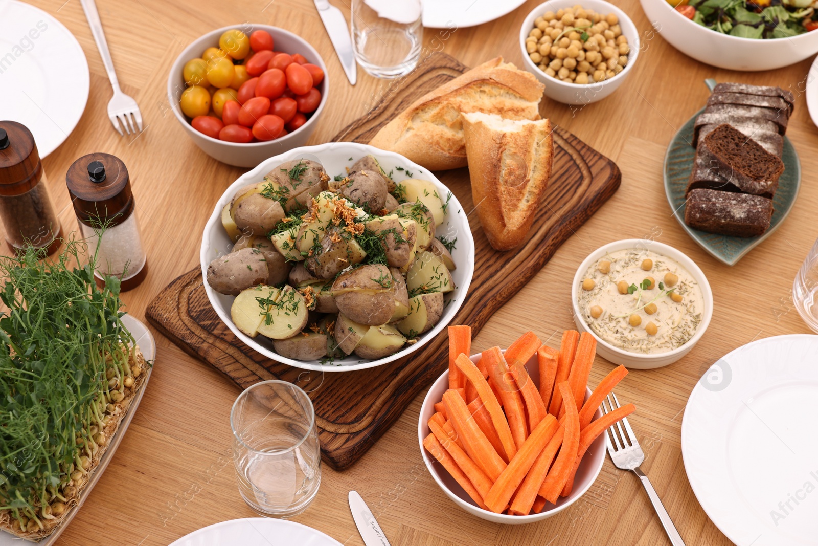 Photo of Healthy vegetarian food, glasses, cutlery and plates on wooden table