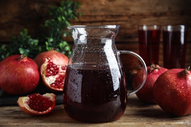Photo of Jug of pomegranate juice and fresh fruits on wooden table