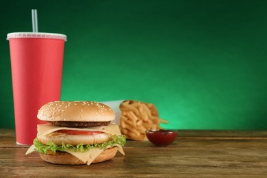 Delicious fast food menu on wooden table against green background. Space for text