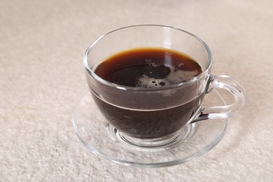 Photo of Delicious coffee in cup on light textured table, closeup