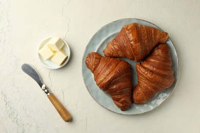 Photo of Plate with tasty croissants served on light textured table, flat lay