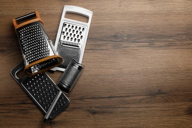 Different modern graters on wooden table, flat lay. Space for text