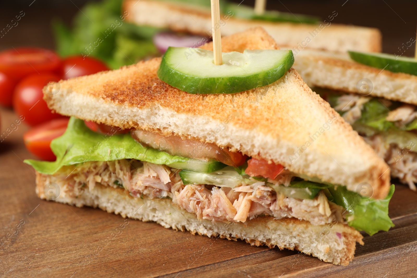 Photo of Delicious sandwiches with tuna and vegetables on wooden board, closeup