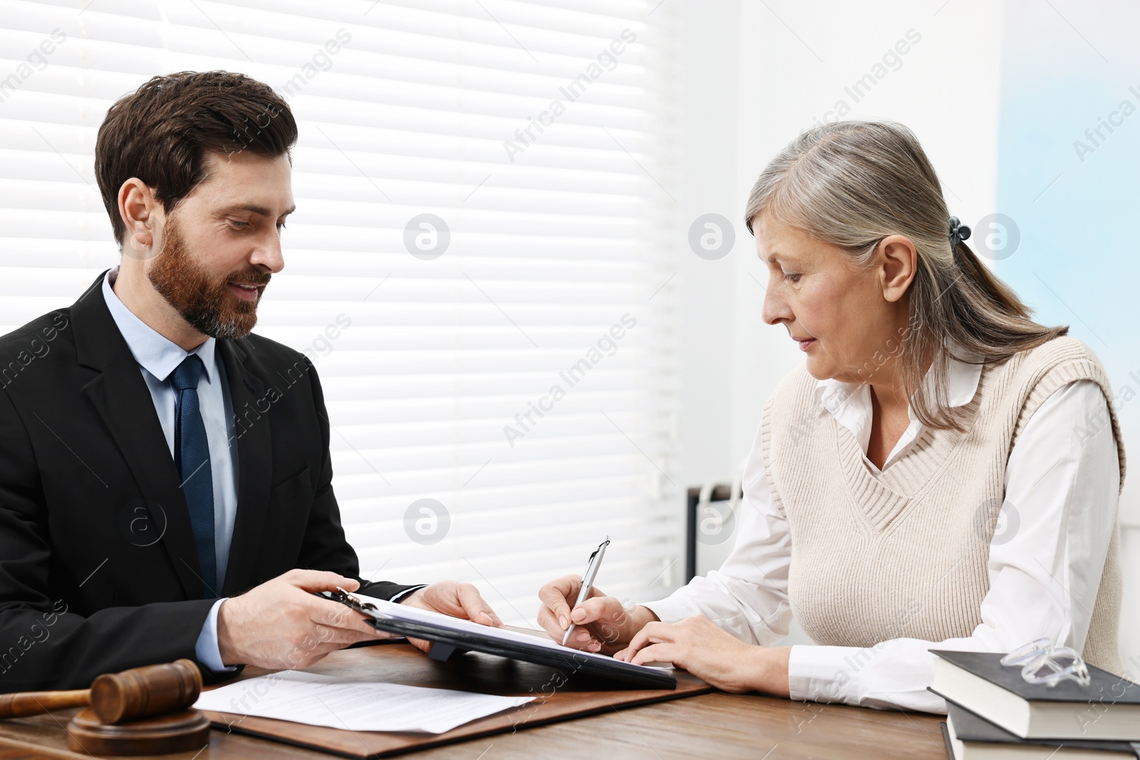 Photo of Senior woman signing document in lawyer's office