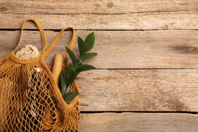 Photo of Net bag with different items on wooden table, top view and space for text. Conscious consumption