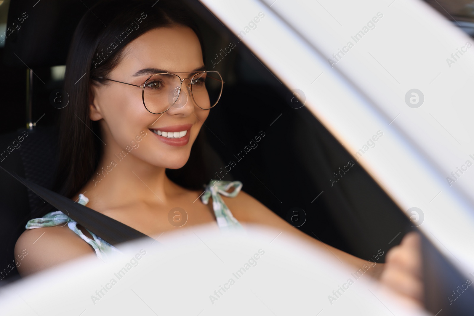 Photo of Enjoying trip. Happy young woman driving her car, view from outside