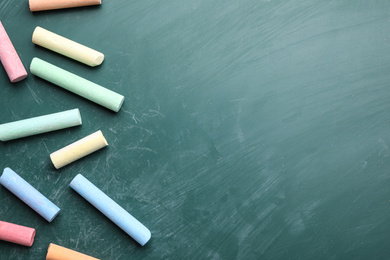 Pieces of color chalk on greenboard, flat lay. Space for text