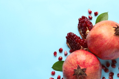 Ripe pomegranates and leaves on color background, top view with space for text