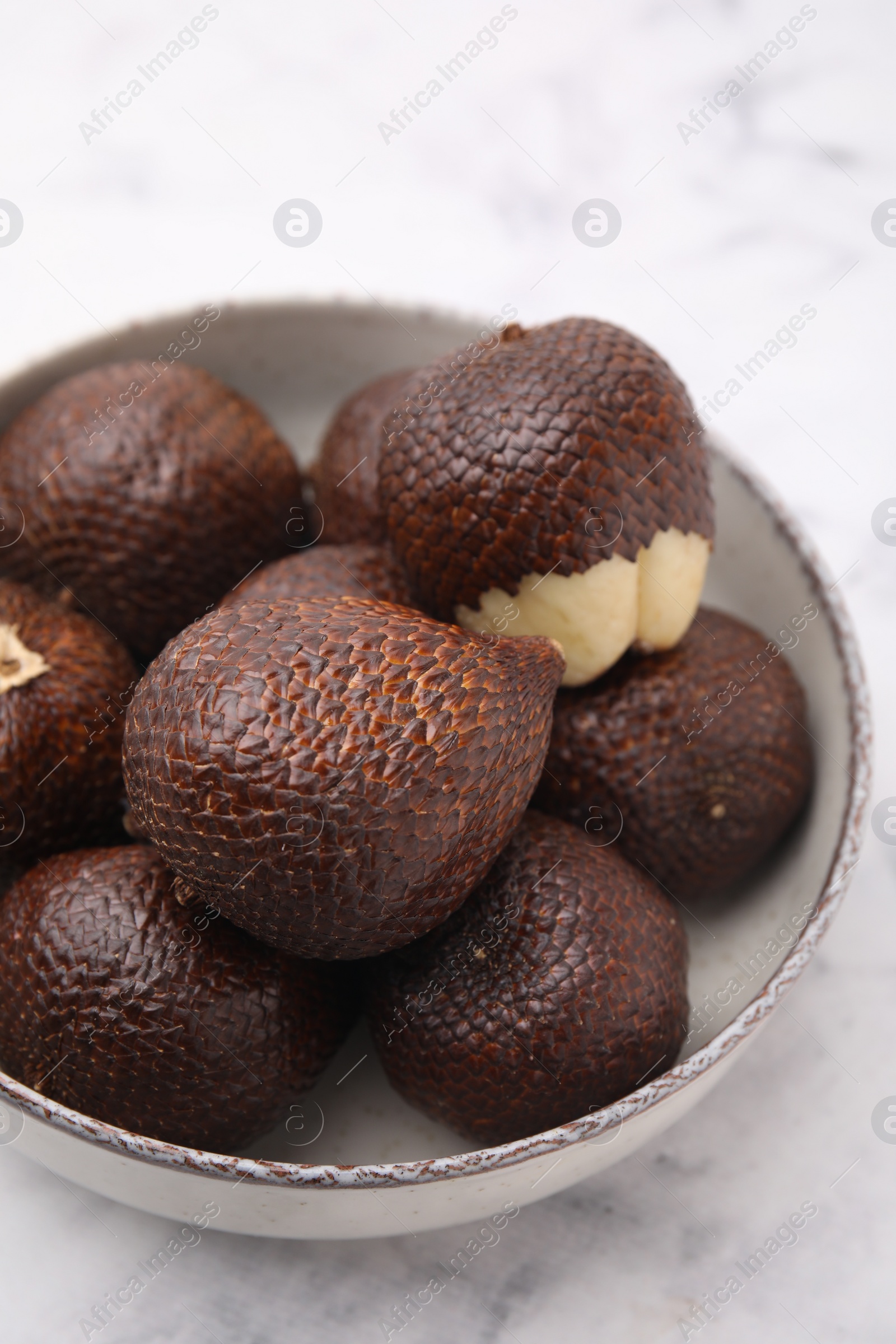 Photo of Fresh salak fruits in bowl on white table, closeup
