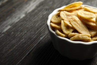 Photo of Bowl with sweet banana slices on wooden  table, space for text. Dried fruit as healthy snack