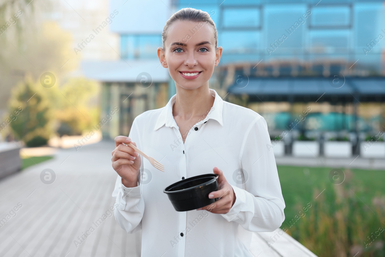 Photo of Portrait of smiling businesswoman with lunch box outdoors