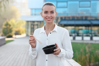 Photo of Portrait of smiling businesswoman with lunch box outdoors