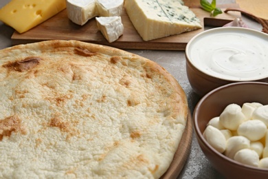Photo of Pizza crust and fresh ingredients on table, closeup