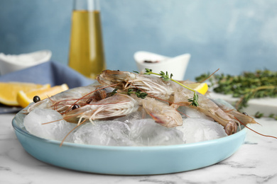 Photo of Raw shrimps with ice on marble table