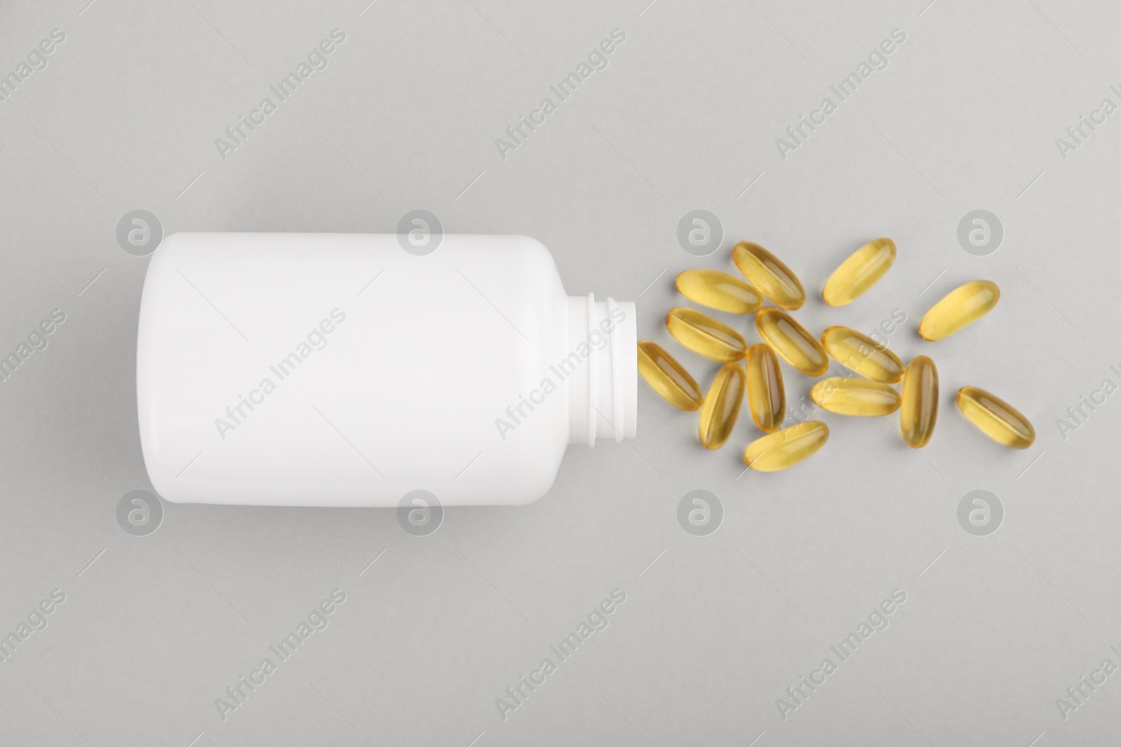 Photo of Bottle and vitamin capsules on light grey background, top view